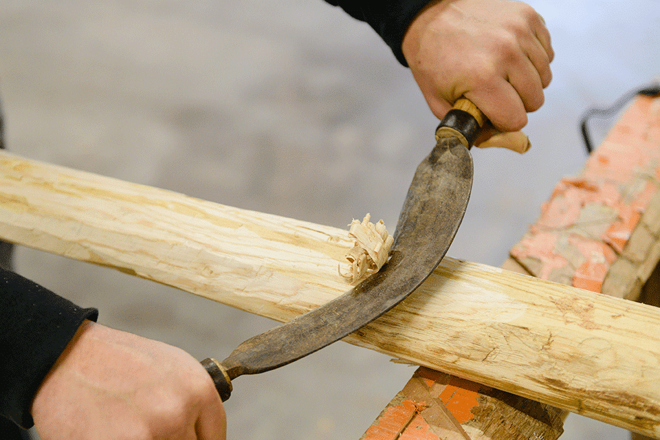 Menuisier Guilbaud et Fils façonnant le bois à la main avec un outil traditionnel