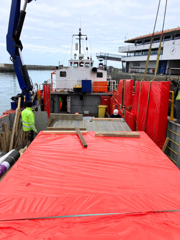 Chargement de panneaux en bois sur une barge pour un chantier de menuiserie à l’île d’Yeu
