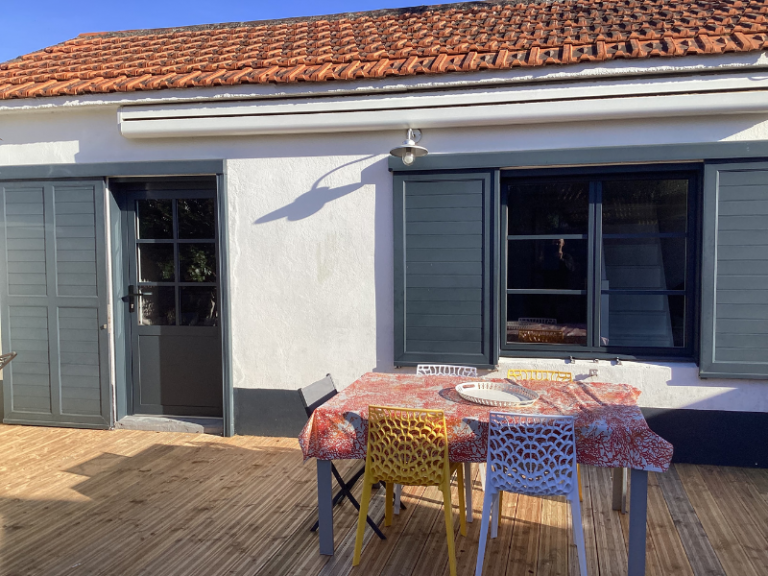 Terrasse en bois avec volets aluminium gris et mobilier coloré