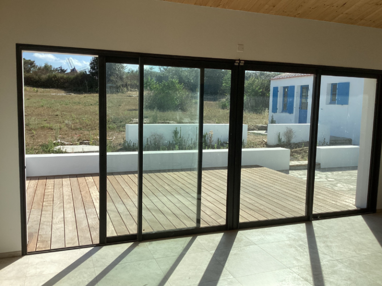Baie vitrée coulissante noire donnant sur terrasse en bois et jardin à l’Île d’Yeu